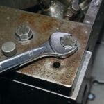 A Beta Tools 3/4-inch combination wrench gripping a large hex bolt on an aged industrial block, showcasing heavy-duty strength and reliability. Get it at Wrenchers.com.