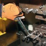 Mechanic using a Beta Tools combination wrench on industrial machinery, applying torque with protective gloves in a workshop setting. Get it at Wrenchers.com