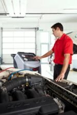 Technician using the Robinair AC1234-4 AC service machine in a repair shop while connected to a vehicle’s A/C system