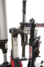 Close-up of the Coats APX90 assist arm assembly featuring vertical cylinders, adjustment controls, operator labels, and the central control switch panel
