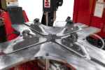 Close-up of the Coats APX90 clamping table with four metal jaws, showing the robust stainless-steel platform and industrial mounting hardware