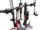 Multiple assist arms and tool heads on the Coats APX90 tire changer, including bead press devices and vertical pneumatic cylinders positioned around the clamping table