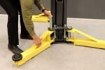 Attaching MaxJax lift arms to columns during portable two-post lift setup.