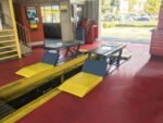 BendPak P-9000LTF flush-mount low-rise lift with open-center pit access and extended approach ramps for low-clearance vehicles.