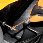 A mechanic uses a Beta Tools T-handle wrench to adjust a fastener on a black and orange motorcycle fairing. The wrench’s long handle provides torque control in tight spaces. Get it at Wrenchers.com.