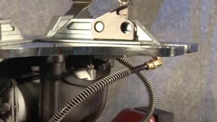 Close-up of the Coats RC-45A bead sealing jet assembly, showing the metal turntable underside, mounting hardware, and coiled air hose with a brass fitting