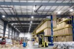 Cool Boss CB-20 HVLS 20-foot industrial ceiling fan installed in a high-bay warehouse, improving airflow and comfort across storage aisles and pallet racks