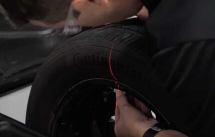Laser-guided line marking the weight placement location on a tire during balancing