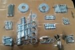 MaxJax portable car lift hardware kit with anchor bolts, washers, pins, and mounting fasteners laid out for installation.
