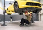 MaxJax M7K two-post lift safety features shown with vehicle elevated in home garage.