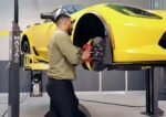 Mechanic performing brake job on yellow sports car using MaxJax M7K portable lift.