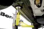 Proper MaxJax two-post lift arm placement under vehicle frame rails.