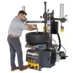 Technician using the R980DP bead lifting tool for precise demounting of stiff sidewall tires. Built to reduce effort while protecting wheels during service. SKU 5140174.