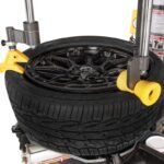 Close-up view of the R980DP tire changer press roller assist arms applying controlled pressure for safe mounting on low-profile and stiff sidewall tires. Ideal for modern performance wheels. SKU 5140174.