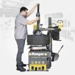 Technician operating the R76ATR-L 110V tire changer, demonstrating efficient mounting and demounting workflow using the assist arm and tilt-back tower