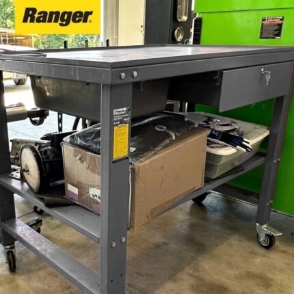 Ranger RWB-1TD teardown workbench in a real customer shop loaded with tools, boxes, and equipment on the shelf beneath the basin