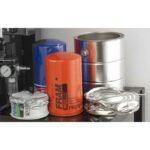 Uncrushed and crushed oil filters positioned beside a paint and oil filter crusher for comparison